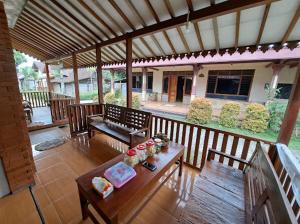 an outdoor patio with a table and benches and a roof at Romadhoni Homestay in Magelang