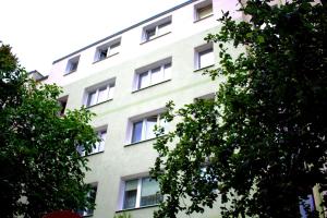 un edificio alto de color blanco con ventanas y árboles en Apartament Morska en Gdynia