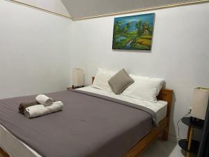 a bedroom with a bed with a painting on the wall at The Iris Vulcano's in Kubupenlokan