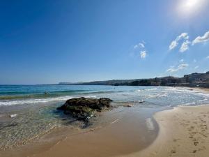 a beach with a rock in the water at mare suites 4 in Chania Town +83 photos