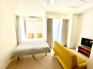 a hotel room with a bed and a yellow couch at Lucky House 喜屋 in Osaka