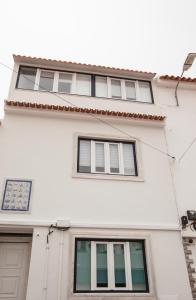 Un edificio blanco con tres ventanas. en Casas Burnay I, en Ericeira