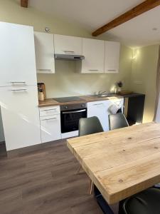 a kitchen with white cabinets and a wooden table at Duplex appartement en plein centre in Gérardmer +1 photo