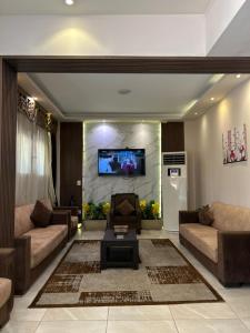 a living room with two couches and a tv on a wall at Jewel Dokki Hotel in Cairo