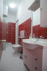 baño con lavabo, aseo y paredes rojas en Apartments Svilan, en Trogir