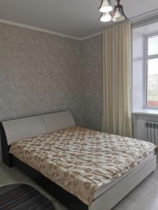 une chambre avec un lit et une fenêtre dans l'établissement 2х комнатная студия в центре, новый дом, à Kostanay