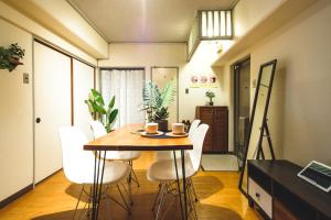 a dining room with a table and white chairs at Rose Heights -vacation rental- in Osaka