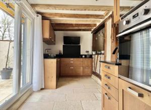 a kitchen with wooden cabinets and a large window at Le terroir des sens in Corgengoux