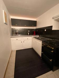 a kitchen with white cabinets and black appliances at L'Oret'Home in Baugé-en-Anjou +12 photos
