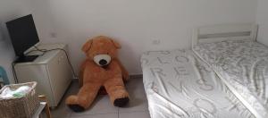 Un oso de peluche marrón sentado junto a una cama en בית פרטי כפרי בהרצליה, en Herzelia 