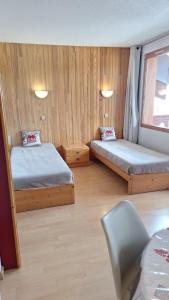 a small room with two beds and a chair at APPART ZIG-ZAG LES COCHES in Les Coches