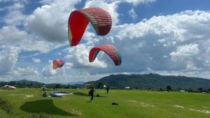 a group of people flying kites in a field at Nivaara in Bīr