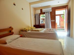 two beds in a room with a window at Pousada Maresias Guriri in Guriri +87 photos