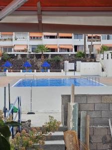 Una piscina con sombrillas azules en un edificio. en Estudio Stephane Chapparal Costa del silencio, en Las Galletas