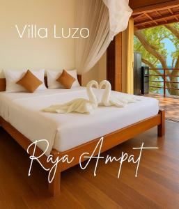a bed with two swans sitting on top of it at Villa Luzo & Tours in Saonek