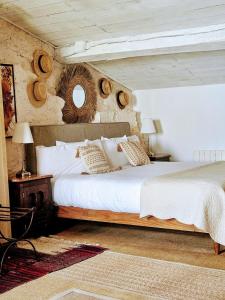 a bedroom with a bed with white sheets and a mirror at La Maison Colline in Saint-Émilion