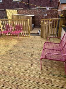 three pink benches sitting on a wooden deck at Lily's Place in Cleethorpes