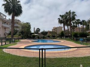 una piscina en un parque con palmeras en Encantador Apartamento dúplex con vistas al mar, en Canet de Berenguer