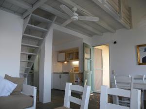 a living room with white chairs and a ceiling fan at Spitakia in Vourkari