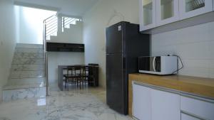 a kitchen with a black refrigerator and a microwave at Villa Dalia Puncak P2-12 in Cianjur