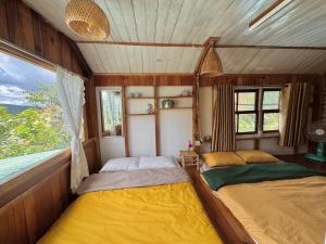 two beds in a train room with a window at Nhà Dưới Đồi Homestay in Ấp Man Ling
