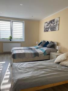 two beds in a bedroom with two windows at Apartament Koszarawa in Koszarawa