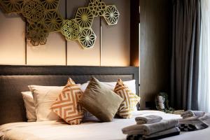 a bedroom with a bed with pillows and a headboard at Suite Aura 1BR PoolsGyms Shuttle to Nai Harn in Rawai Beach +21 photos