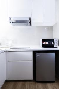 a kitchen with a counter with a microwave and a dishwasher at Suite Aura 1BR PoolsGyms Shuttle to Nai Harn in Rawai Beach