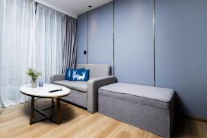 a living room with a chair and a table at Suite Aura 1BR PoolsGyms Shuttle to Nai Harn in Rawai Beach