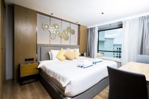 a bedroom with a large white bed and a window at Suite Aura 1BR PoolsGyms Shuttle to Nai Harn in Rawai Beach
