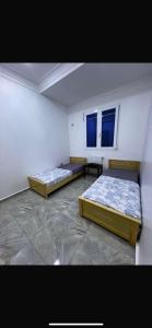 two beds in a room with two windows at Appartement familial et calme proche des plages & Alger in Mahelma