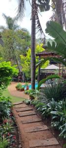 a garden with a pathway with plants and a palm tree at African Diamond - Date Night Suite in Benoni