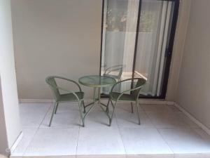 a glass table and two chairs on a balcony at Kasane Boutique House in Kasane