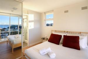 a bedroom with a large white bed with red pillows at Panoramic Harbour View Apartment in Sydney