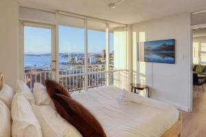 a bedroom with a bed and a balcony with a view at Panoramic Harbour View Apartment in Sydney