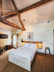 una camera da letto con un grande letto bianco e soffitti in legno di La Ferme du Cerf Bleu a Sanvigné