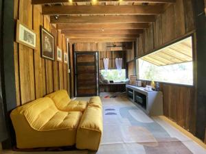 a living room with a yellow couch in a room at Vela Resort Umphang in Ban Mae Klong Mai