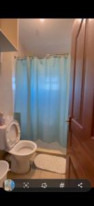 a bathroom with a toilet and a blue shower curtain at Madaraka 1 Westpointe in Nairobi