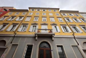 Edificio amarillo con ventanas blancas y balcón en RivApartments2 with private parking, en Trieste