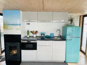 a kitchen with white cabinets and a blue refrigerator at Hausboot Hafenkönig Lübeck in Lübeck