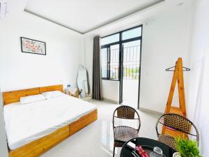 a bedroom with a bed and chairs and a large window at Vũ Trâm Homestay in Thôn Dương Xuân Hạ