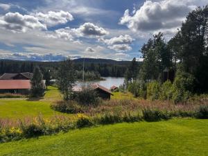 a view of a field with a lake and a barn at Hildas Hus with river view and spa in Särna