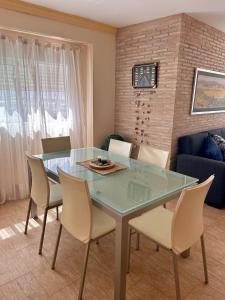 a dining room with a glass table and chairs at Apartamento playa Valencia, Mareny Blau in Mareny Blau