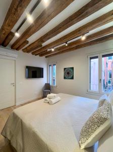Un dormitorio con una gran cama blanca y ventanas. en Ca Ducale 2 min da Piazza San Marco e Palazzo Ducale, en Venecia