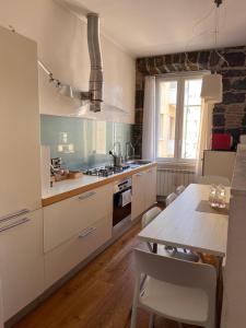 a kitchen with white cabinets and a dining table at RivApartments2 FREE private parking in Trieste