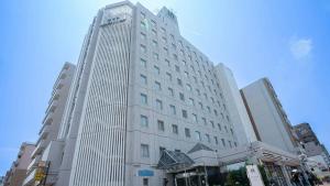 Un edificio alto y blanco en una calle de la ciudad. en Hotel Casabella Inn Kobe, en Kobe