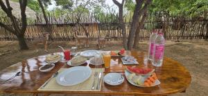 einen Holztisch mit Teller mit Speisen und Getränken darauf in der Unterkunft Thumbaya Resort Yala in Tissamaharama