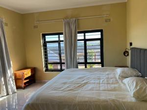 a bedroom with a large bed and two windows at The Cozy Nook in Blantyre