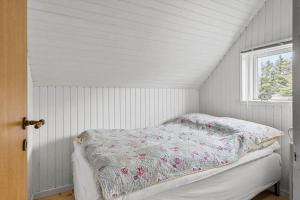 Un dormitorio blanco con una cama con un edredón floral. en 20045-Ulfborg-Hummelmosevej-5, en Sundhuse