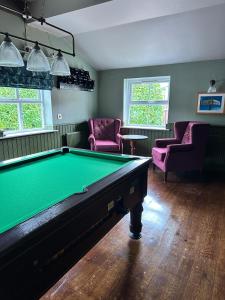 a billiard room with a pool table and pink chairs at Feildens Arms Hotel in Blackburn